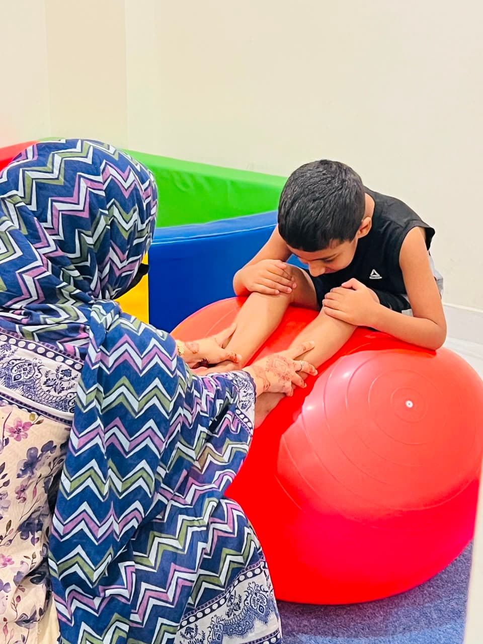 Physical therapist working with a child on a therapy ball at NEST, Islamabad